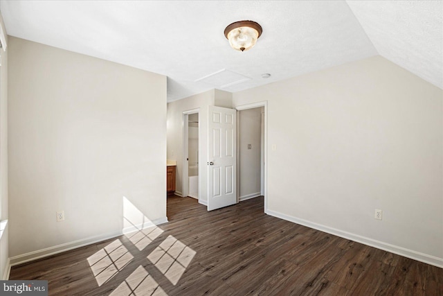 unfurnished bedroom with dark wood-type flooring and vaulted ceiling