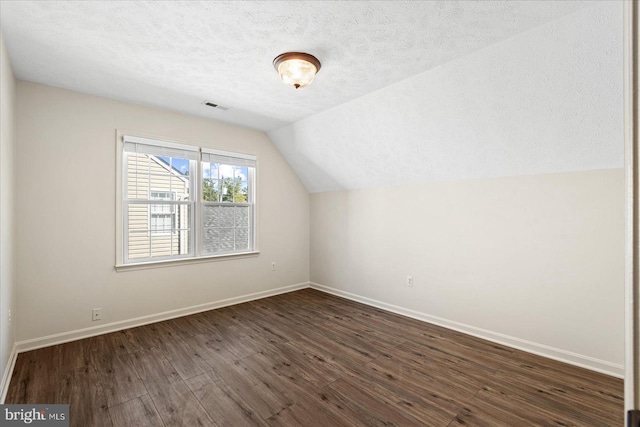 bonus room with a textured ceiling, lofted ceiling, and dark wood-type flooring