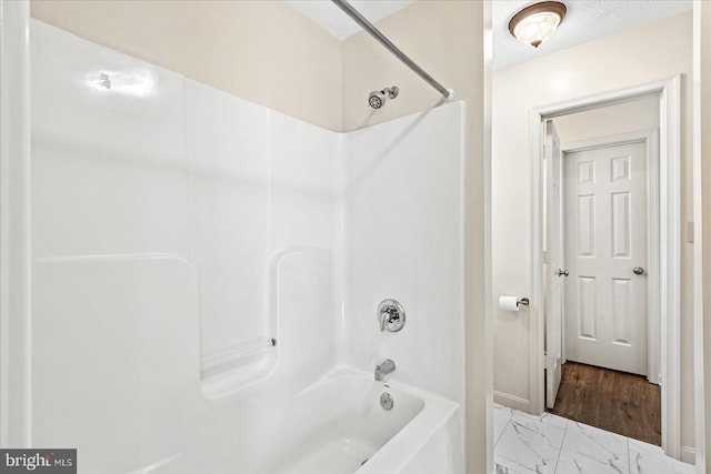 bathroom featuring shower / bathtub combination and a textured ceiling