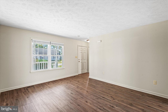 empty room with dark hardwood / wood-style floors and a textured ceiling