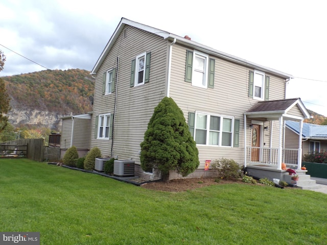 view of side of home with a yard, a mountain view, and central AC unit