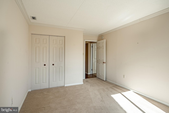 unfurnished bedroom featuring a closet, light carpet, a textured ceiling, and ornamental molding