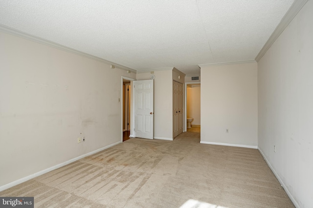 unfurnished bedroom featuring light carpet, a textured ceiling, connected bathroom, and ornamental molding