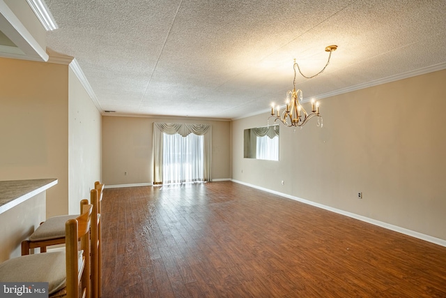 spare room with hardwood / wood-style floors, crown molding, a notable chandelier, and a textured ceiling