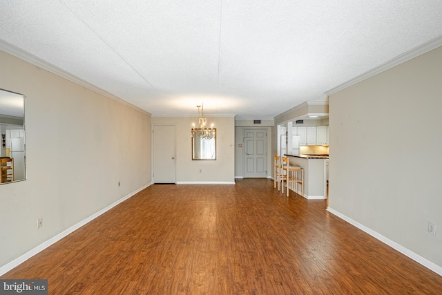 unfurnished living room with an inviting chandelier, crown molding, a textured ceiling, and hardwood / wood-style flooring