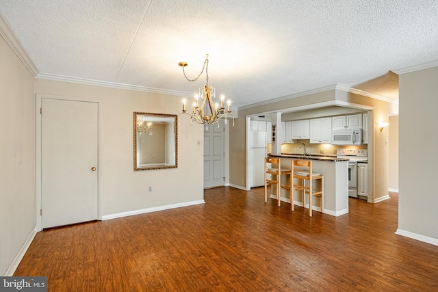 interior space featuring dark hardwood / wood-style flooring, an inviting chandelier, a textured ceiling, ornamental molding, and sink