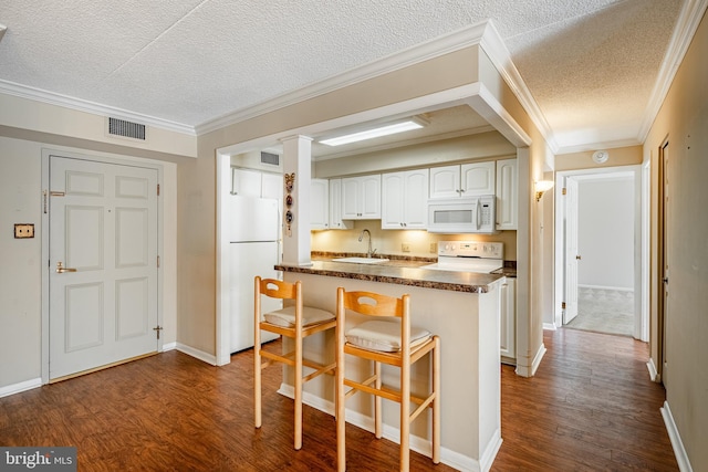 kitchen with white appliances, sink, a textured ceiling, kitchen peninsula, and white cabinets