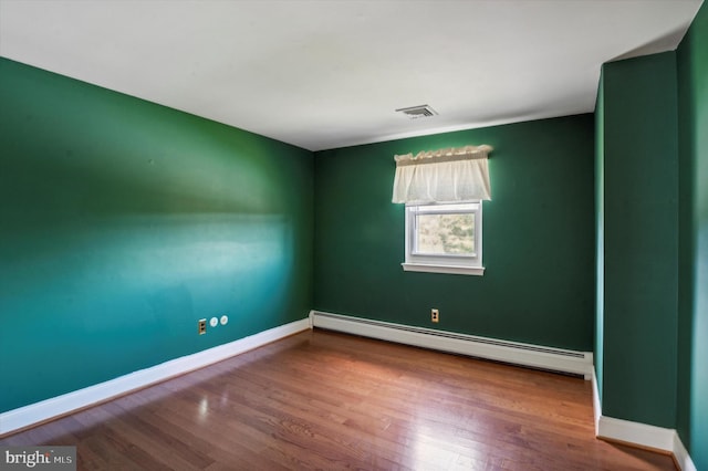 spare room featuring hardwood / wood-style floors and a baseboard heating unit