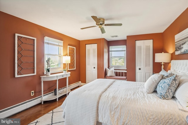 bedroom featuring ceiling fan, a baseboard radiator, multiple windows, and multiple closets