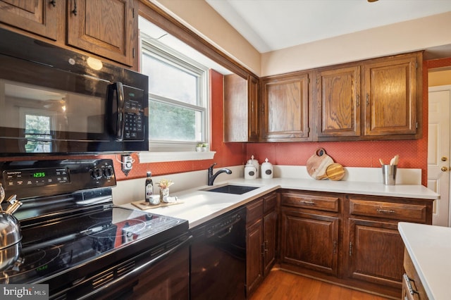 kitchen with sink, black appliances, and light wood-type flooring