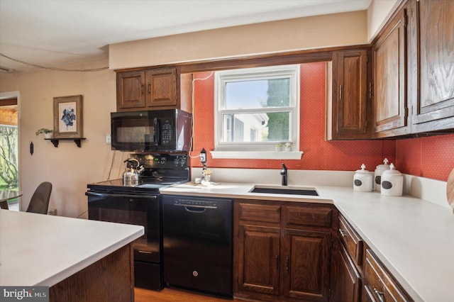 kitchen featuring black appliances, dark brown cabinetry, and sink