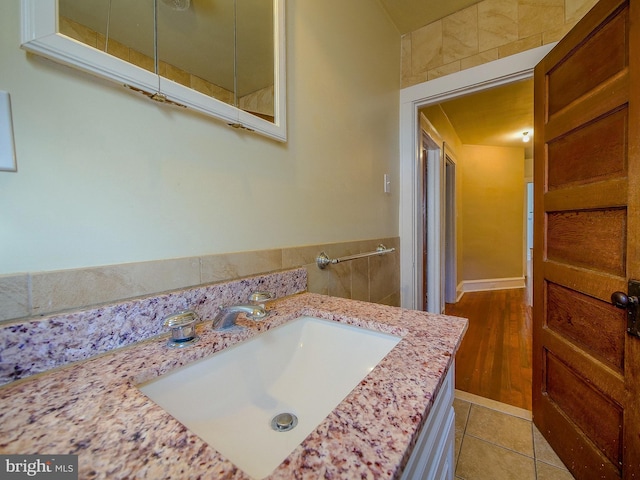 bathroom with tile walls, vanity, and wood-type flooring