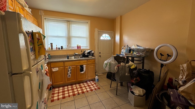 kitchen featuring white refrigerator, light tile patterned floors, and sink