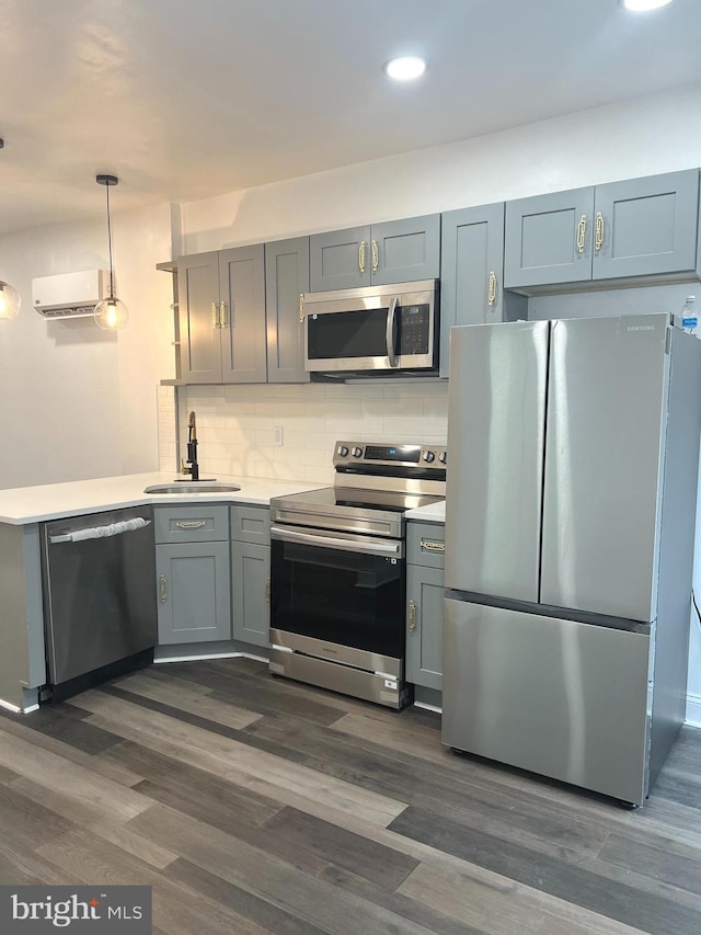 kitchen featuring appliances with stainless steel finishes, dark hardwood / wood-style flooring, backsplash, a wall unit AC, and sink