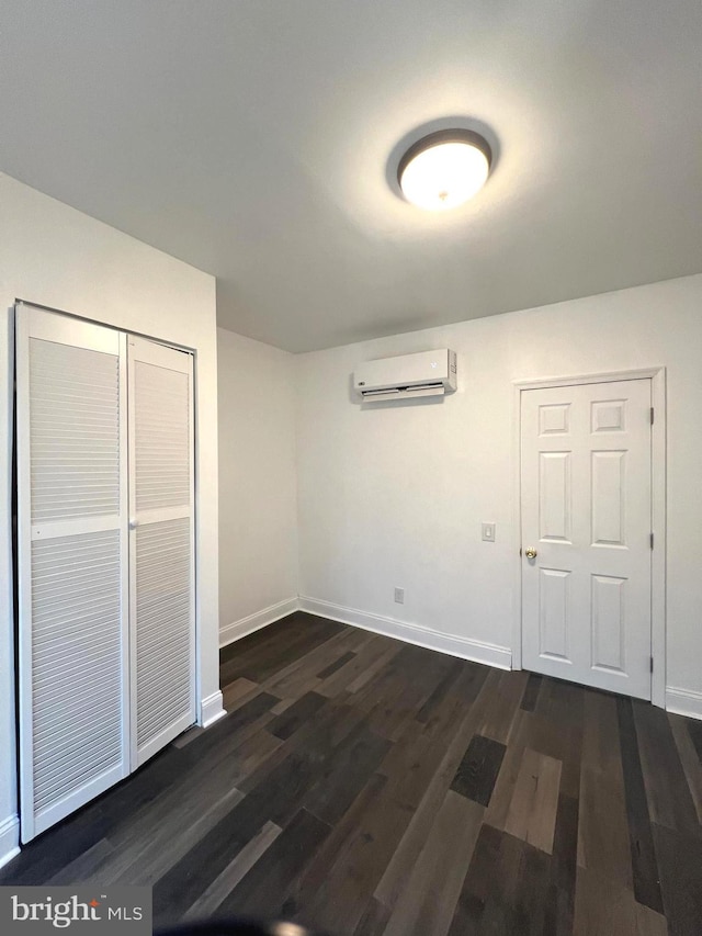 unfurnished bedroom with a closet, a wall mounted AC, and dark wood-type flooring