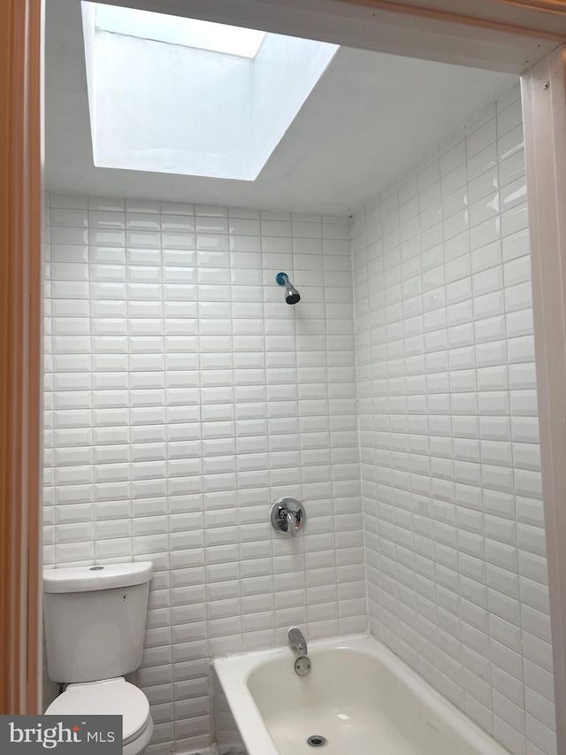 bathroom with shower / bathing tub combination, toilet, and tile walls