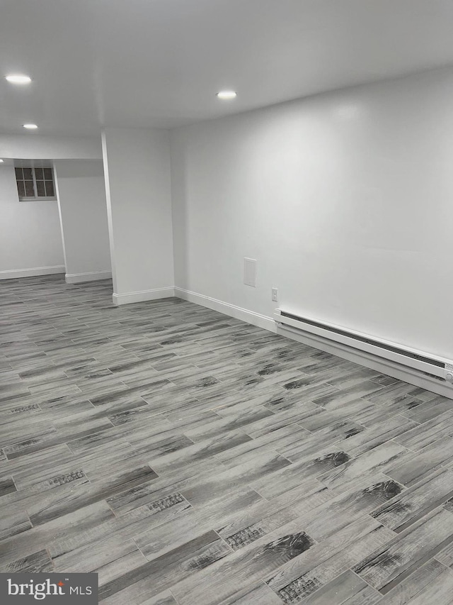 unfurnished room featuring a baseboard radiator and light hardwood / wood-style floors