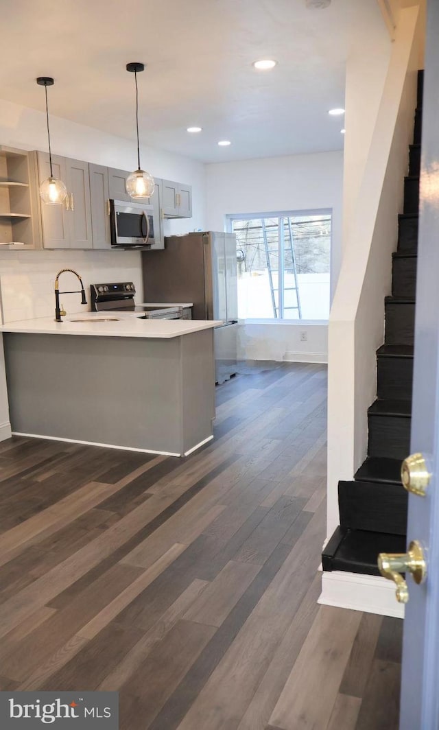 kitchen featuring gray cabinetry, sink, stainless steel appliances, dark wood-type flooring, and kitchen peninsula