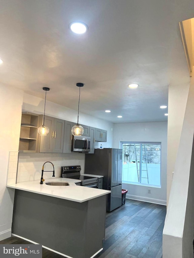 kitchen with kitchen peninsula, pendant lighting, stainless steel appliances, and sink