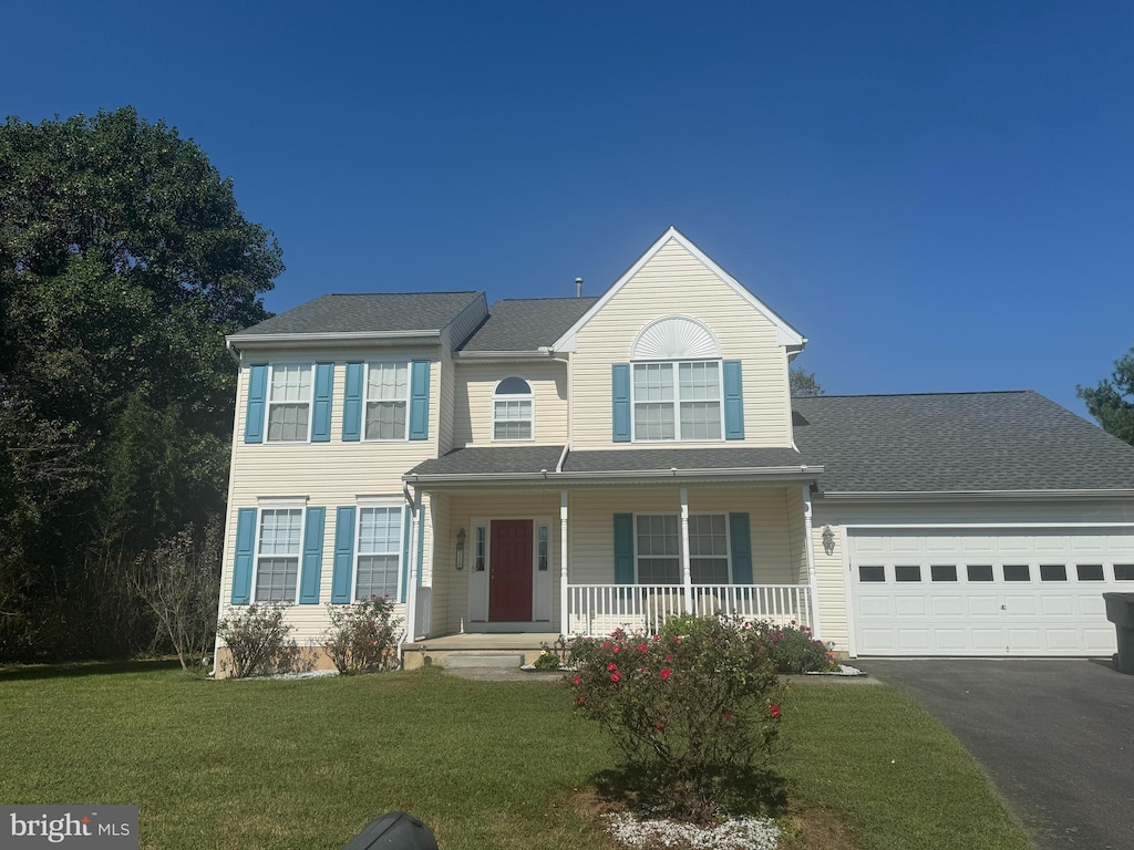 view of front facade featuring a garage, a front yard, and covered porch