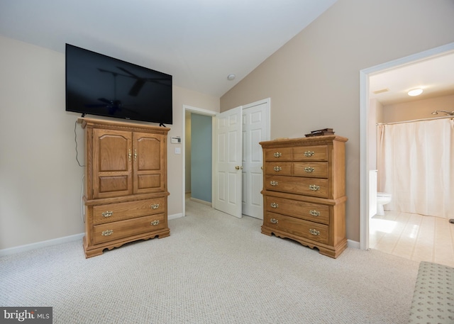 carpeted bedroom featuring vaulted ceiling and connected bathroom