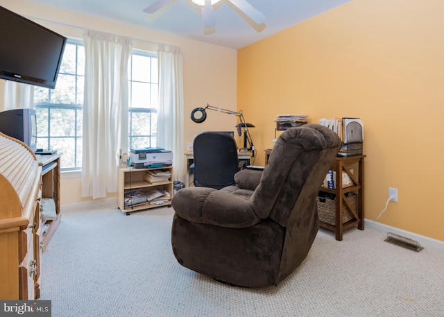 living area featuring ceiling fan, plenty of natural light, and carpet