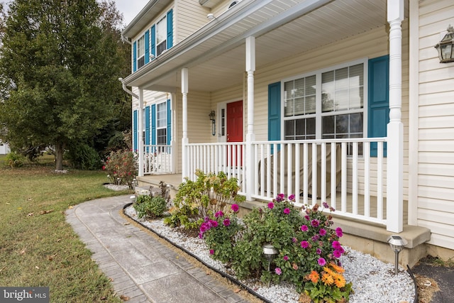 view of exterior entry featuring a yard and covered porch