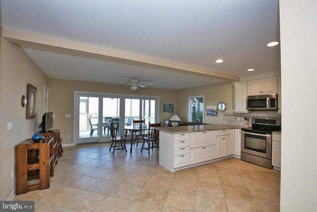 kitchen with white cabinets, stainless steel appliances, kitchen peninsula, and decorative backsplash