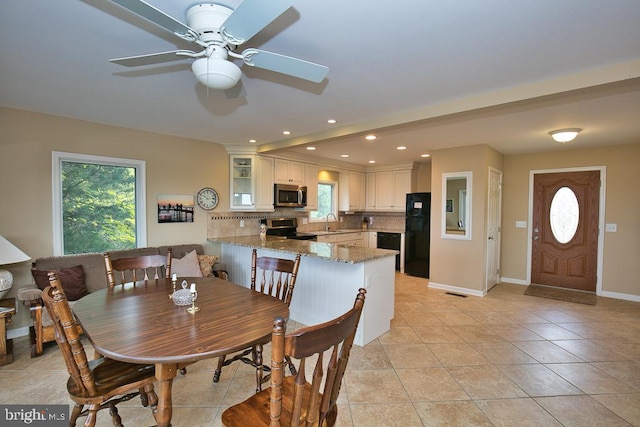 tiled dining area featuring ceiling fan and sink