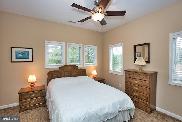 bedroom with light colored carpet, multiple windows, and ceiling fan