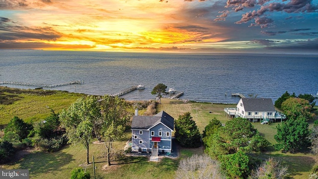 aerial view at dusk featuring a water view