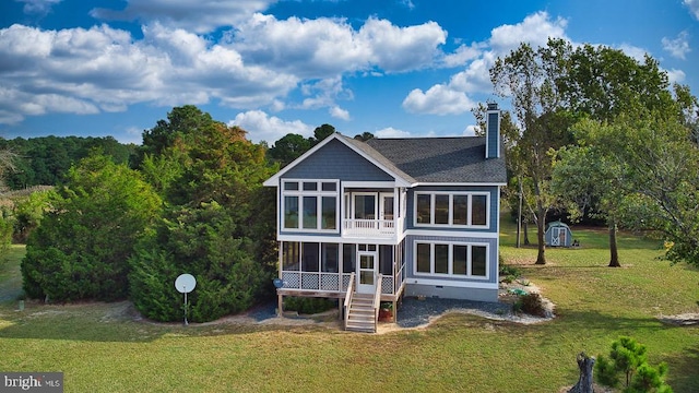 back of property featuring a sunroom, a yard, and a shed