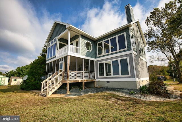 rear view of house featuring a balcony, a sunroom, and a lawn