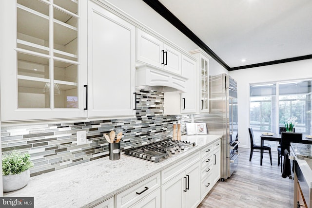 kitchen featuring backsplash, appliances with stainless steel finishes, white cabinets, and light hardwood / wood-style floors