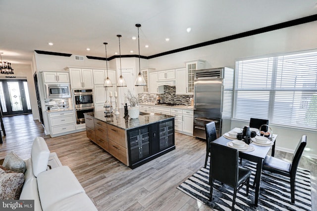 kitchen featuring a kitchen island, hanging light fixtures, stainless steel appliances, and a healthy amount of sunlight