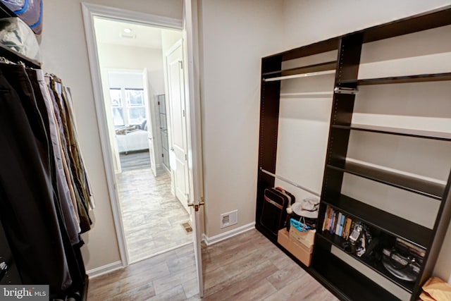 walk in closet with light hardwood / wood-style flooring