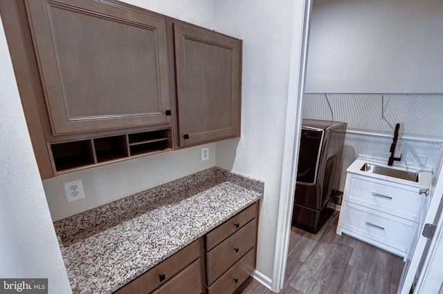 kitchen featuring light stone countertops, sink, light hardwood / wood-style floors, and separate washer and dryer