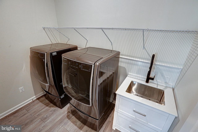 laundry area featuring sink, light wood-type flooring, cabinets, and separate washer and dryer