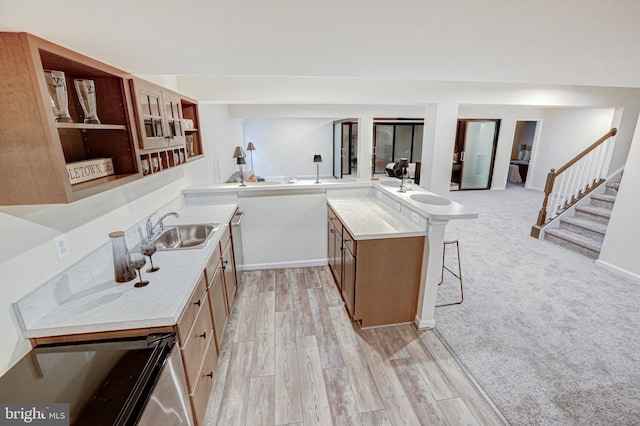 kitchen with light hardwood / wood-style floors, kitchen peninsula, sink, and a breakfast bar