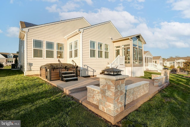 rear view of house with an outdoor fire pit, a patio area, a lawn, and a sunroom