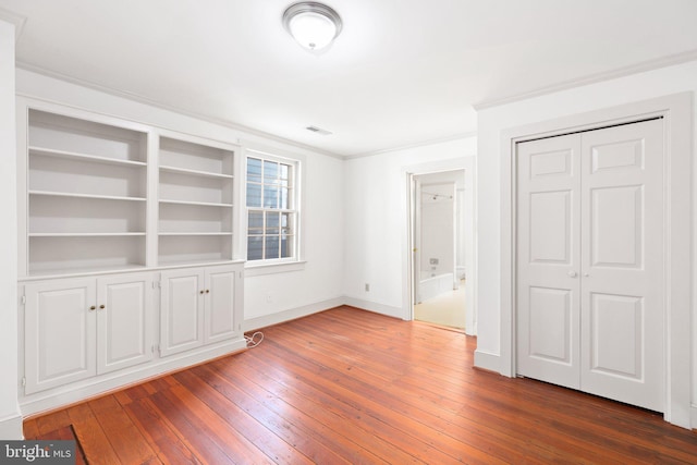 unfurnished bedroom with hardwood / wood-style flooring, a closet, and crown molding