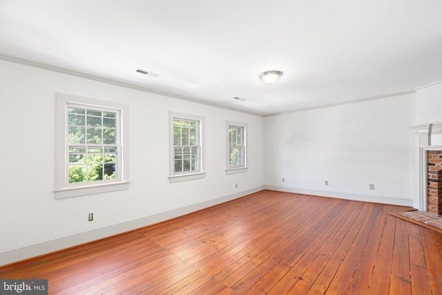 unfurnished living room featuring wood-type flooring, crown molding, and a brick fireplace