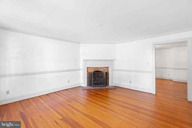 unfurnished living room with light hardwood / wood-style floors, ornamental molding, and a brick fireplace