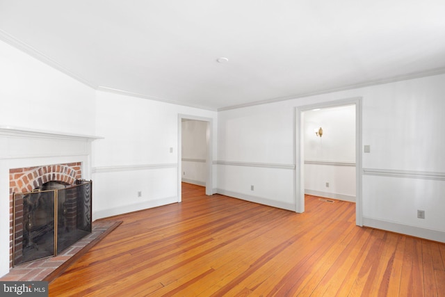 unfurnished living room featuring a brick fireplace, light wood-type flooring, and crown molding