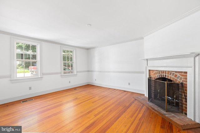 unfurnished living room featuring wood-type flooring, a fireplace, and crown molding