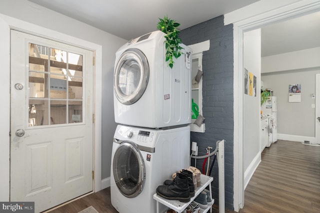 washroom featuring brick wall, dark hardwood / wood-style floors, and stacked washer and dryer