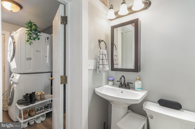 bathroom featuring hardwood / wood-style floors, stacked washer and clothes dryer, and toilet