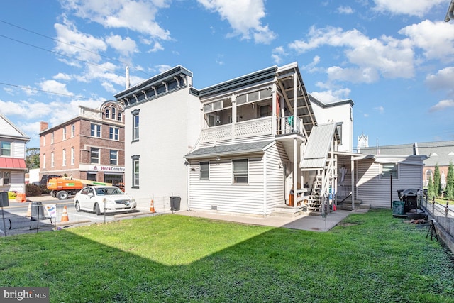 rear view of property with a patio, a balcony, and a lawn