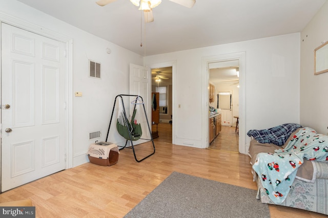 sitting room with ceiling fan and light wood-type flooring