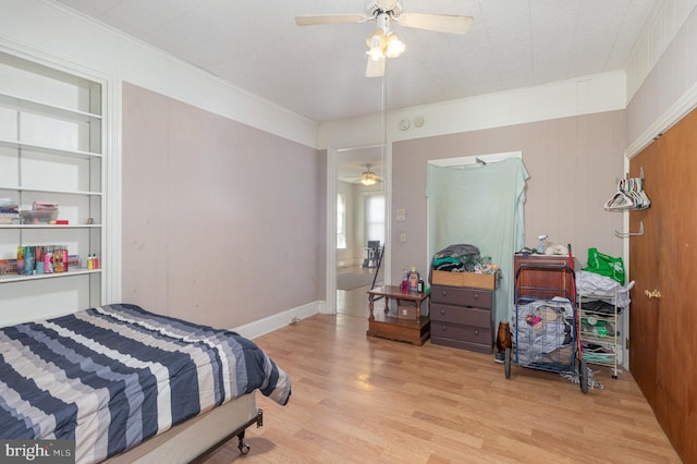 bedroom with ceiling fan, wooden walls, light hardwood / wood-style flooring, and ornamental molding